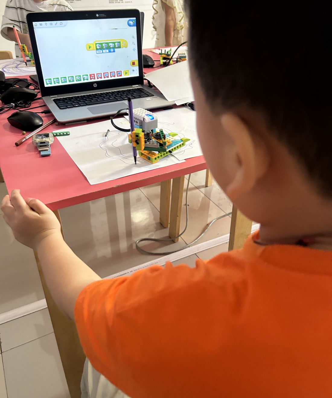 孩子在课堂上用电脑编程,控制自己搭的画图机器人